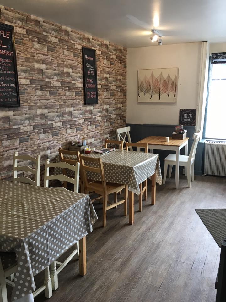 The café seating area with wooden tables, spotted tablecloths and light chairs